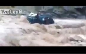 شاهد فيضان هائل يجرف حافلة صغيرة بركابها
