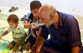 شاهد.. طفل عراقى يطعم والده المبتورة يداه فى إفطار رمضان
