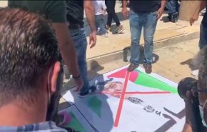 شاهد.. فلسطينيون يدعسون صورة إبن زايد وترامب ونتنياهو