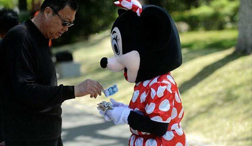 بالصور.. امرأة بملابس «ميكي ماوس» لجمع الأموال لعلاج زوجة ابنها